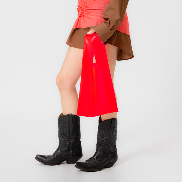 SPARK neon coral latex bag shaped like a classic plastic shopping bag with sculptural cutout handles by Dorilou